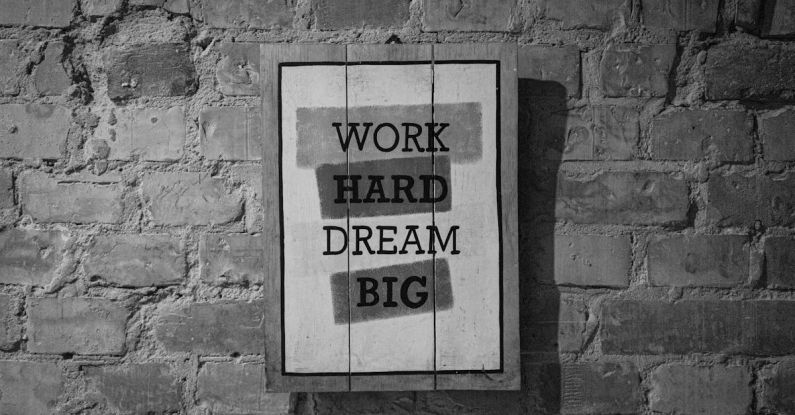 HR Big Data - Black and white frame with inspirational Work Hard Dream Big inscription hanging on brick wall