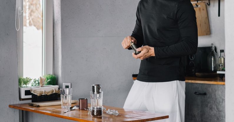 Employee Satisfaction - Man in Black Long Sleeve Shirt and White Pants Standing Beside Brown Wooden Table