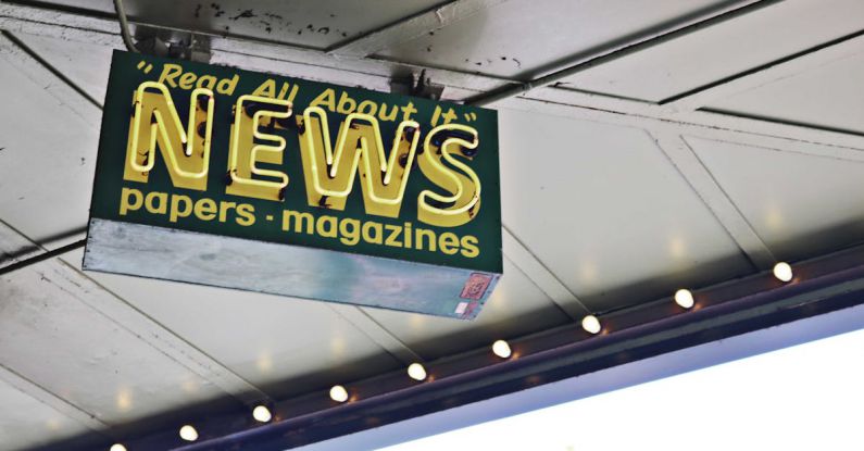 Green Marketing - From below of illuminated signboard with news papers magazines inscriptions hanging on metal ceiling on street