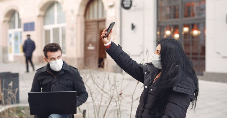 Project Risk - Young couple wearing medical masks using laptop and smartphone on city street